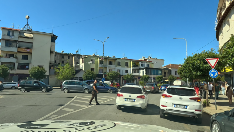 Drukke rotonde in Albanië met in file rijdende auto’s.