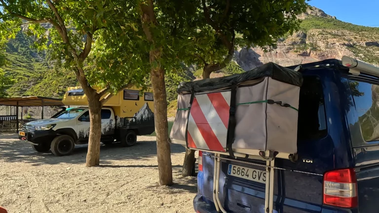 Camper Monty geparkeerd onder bomen bij restaurant I Love Koman.