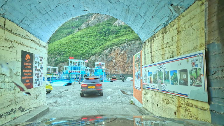 Uitzicht vanuit de tunnel op de kade, ferry en Komani Lake.