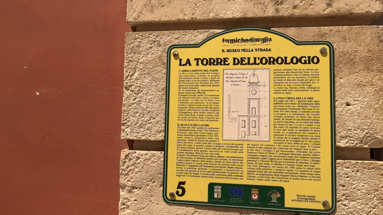 Uitlegbord over Torre dell’Orologio met tekst en afbeelding van de klokkentoren