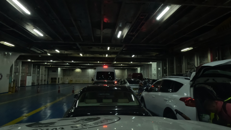 Monty wacht op het autodek van de ferry van Igoumenitsa naar Brindisi tussen andere auto's.