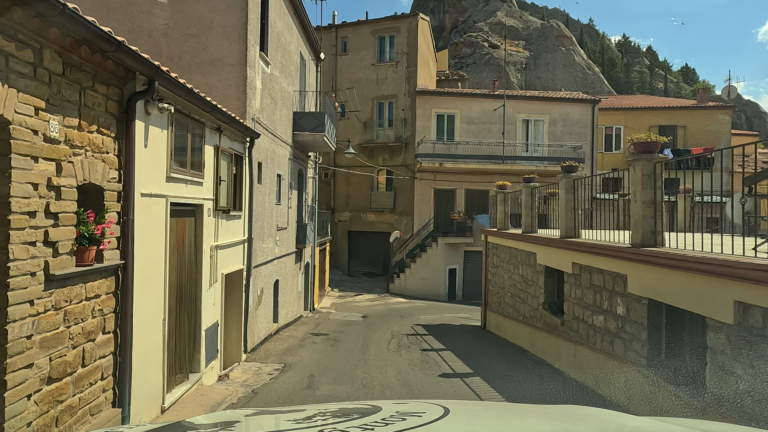 De rit richting Laceno loopt door een smal straatje in Pietrapertosa, met huizen en kleine balkons direct langs de weg.