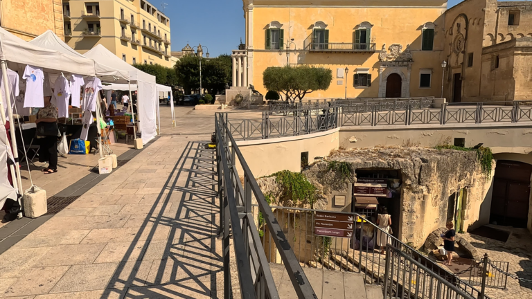 Tijdens een bezoek aan Matera kijk ik vanaf Piazza Vittorio Veneto naar de ingang van Palombaro Lungo