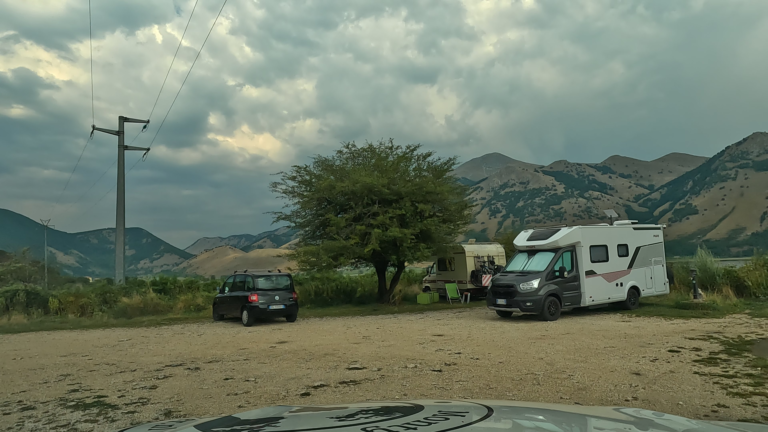 Een mooie route door Campania leidt naar Lago Matese, waar campers en auto's op een gravelparkeerplaats voor het Apennijnengebergte staan.