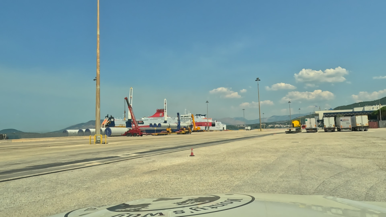 Monty rijdt over het haventerrein tussen vrachtwagens en veerboten ichting de veerboot van Igoumenitsa naar Brindisi.